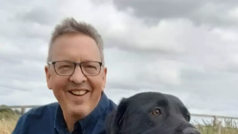 A photo of Richard Cooper with a black Labrador.