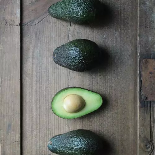 Four avocado halves arranged in a line. The third one is sliced side up.
