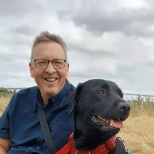 A photo of Richard Cooper with a black Labrador.